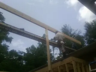 Carpenter setting a ridge beam over a new addition frame — Ice Dam Removal by Roofing Brothers in Fairhope