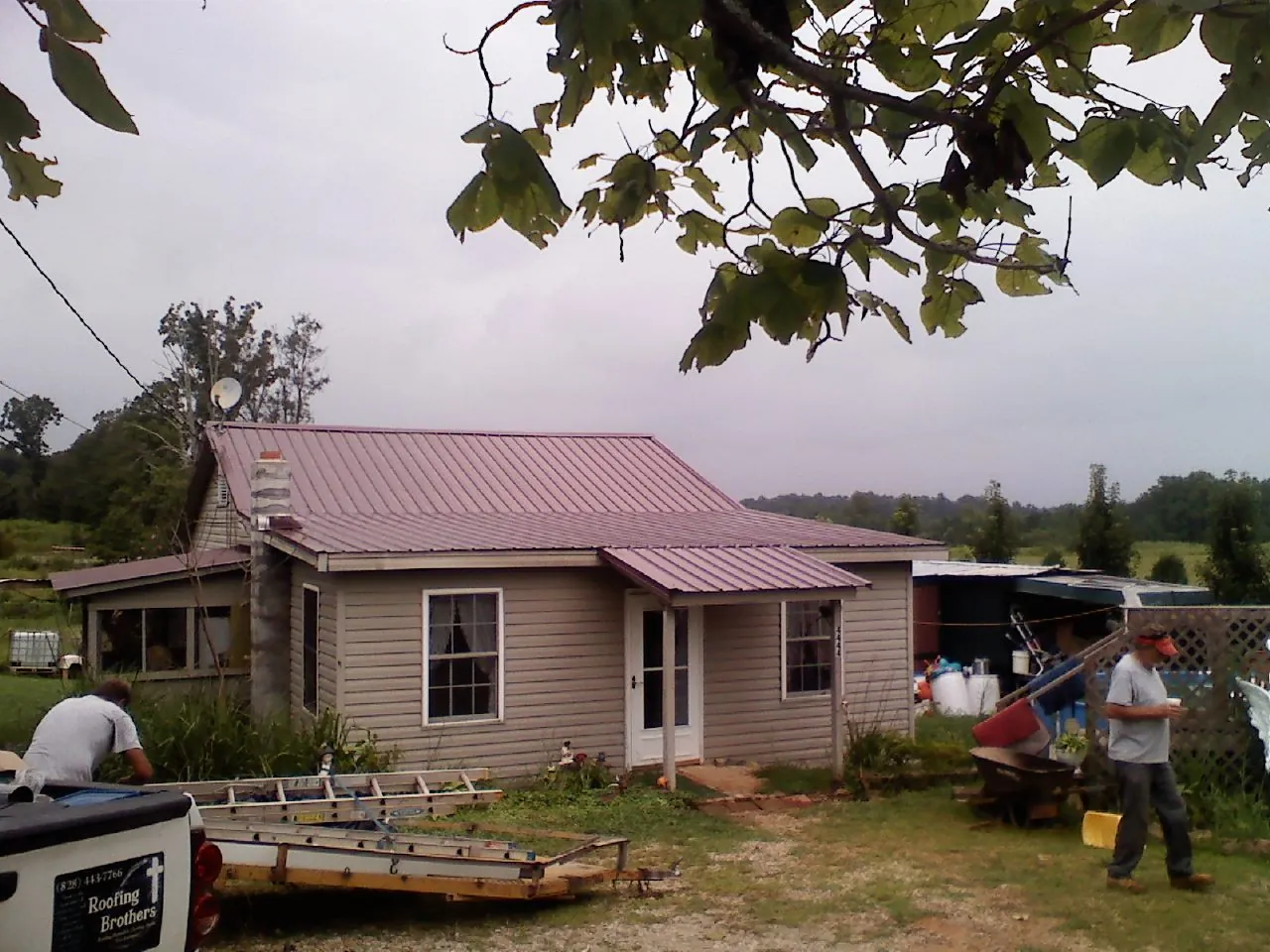 Crew finishing a mauve metal roof on a small farmhouse in Fairhope